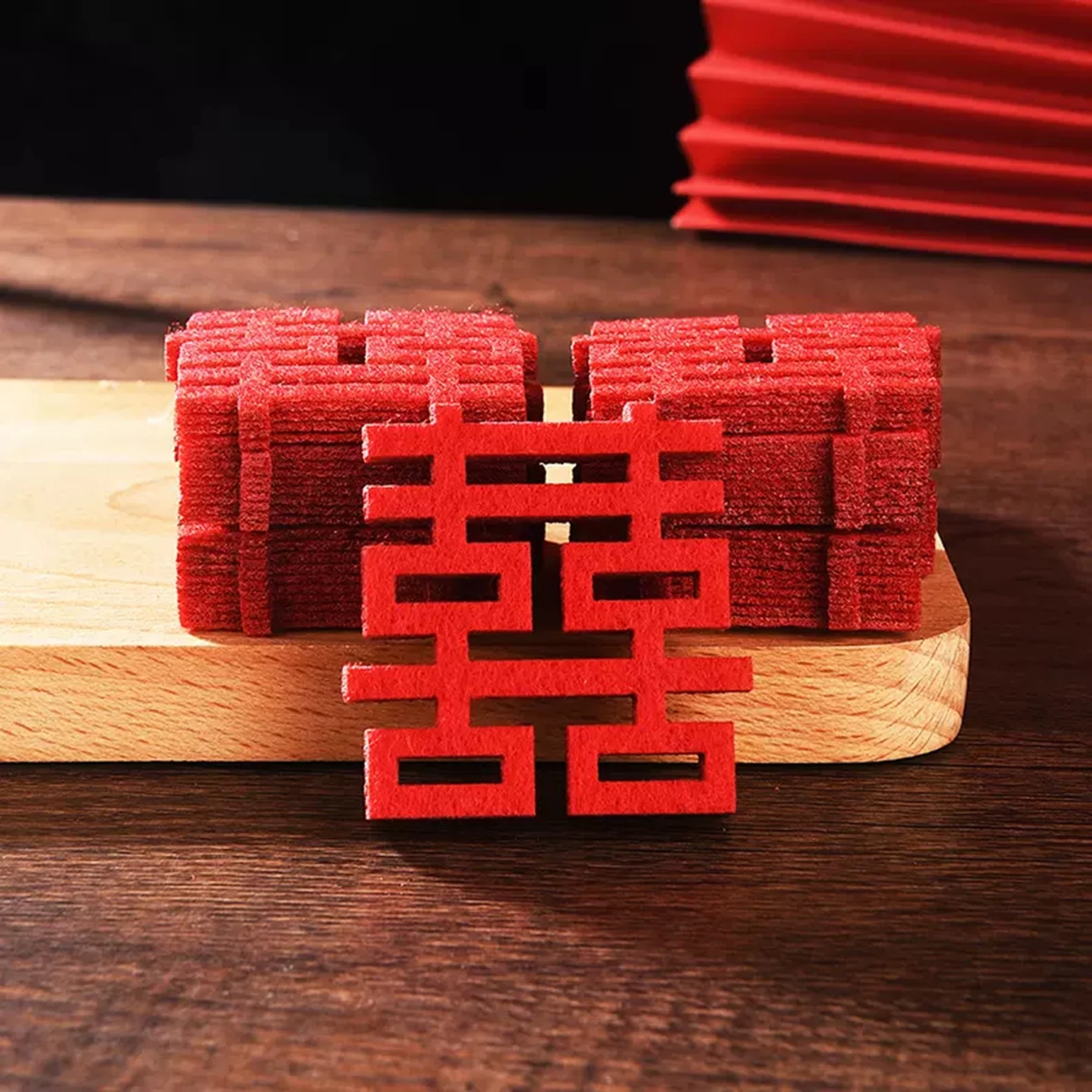 May include: A stack of red felt double happiness Chinese wedding symbols. The symbols are cut out in a traditional design and are perfect for adding a touch of Chinese culture to your wedding decor.