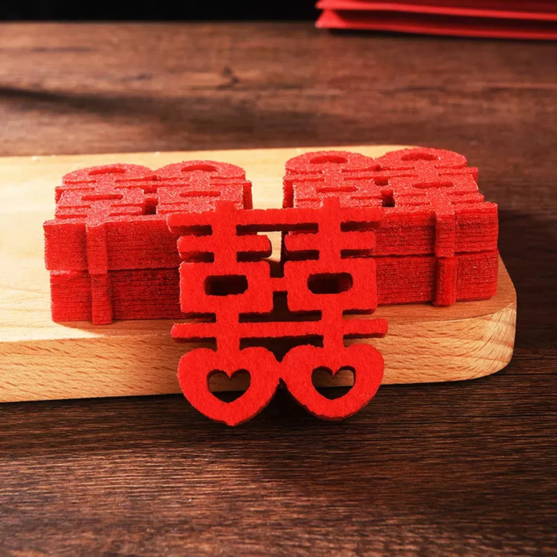 May include: A stack of red felt double happiness wedding decorations with two hearts at the bottom.