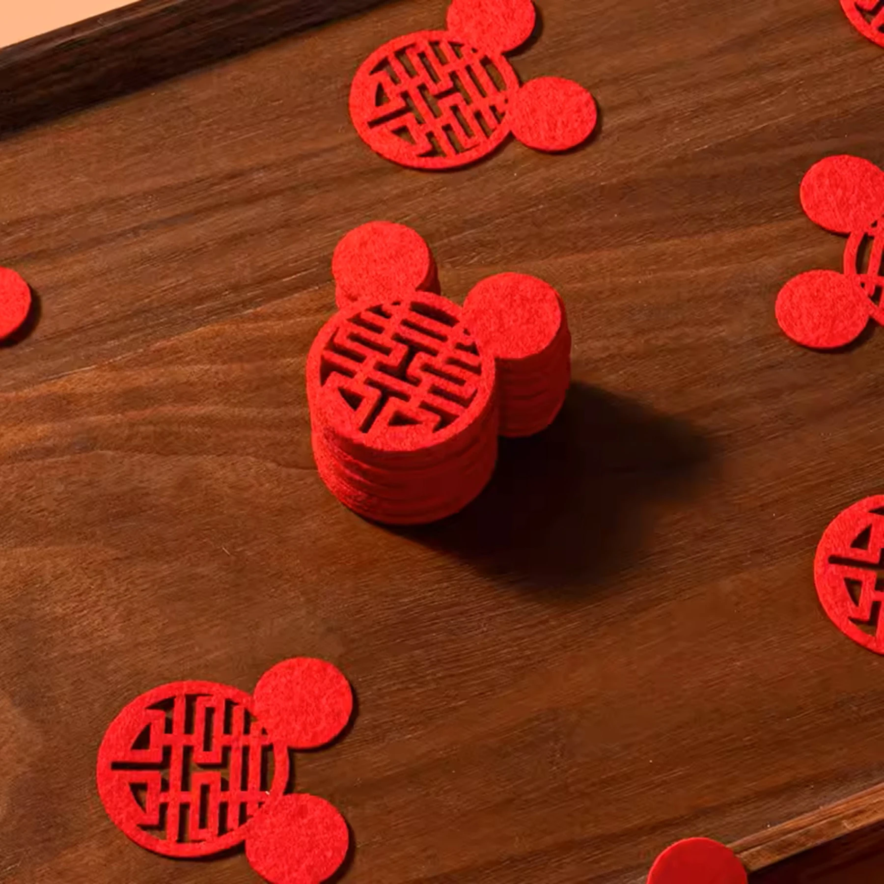 May include: Red felt mouse-shaped decorations with a Chinese double happiness symbol cut out in the center. The decorations are scattered on a wooden surface.