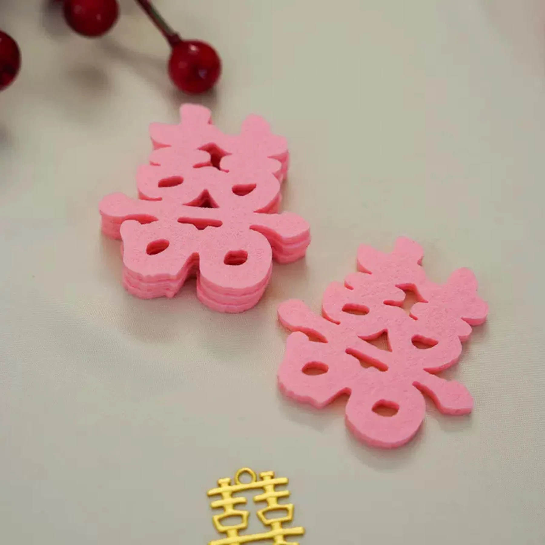 May include: Two pink felt cutouts of the Chinese character for "double happiness" or "double joy", which is a traditional symbol used in Chinese weddings. A gold metal charm with the same character is also shown.