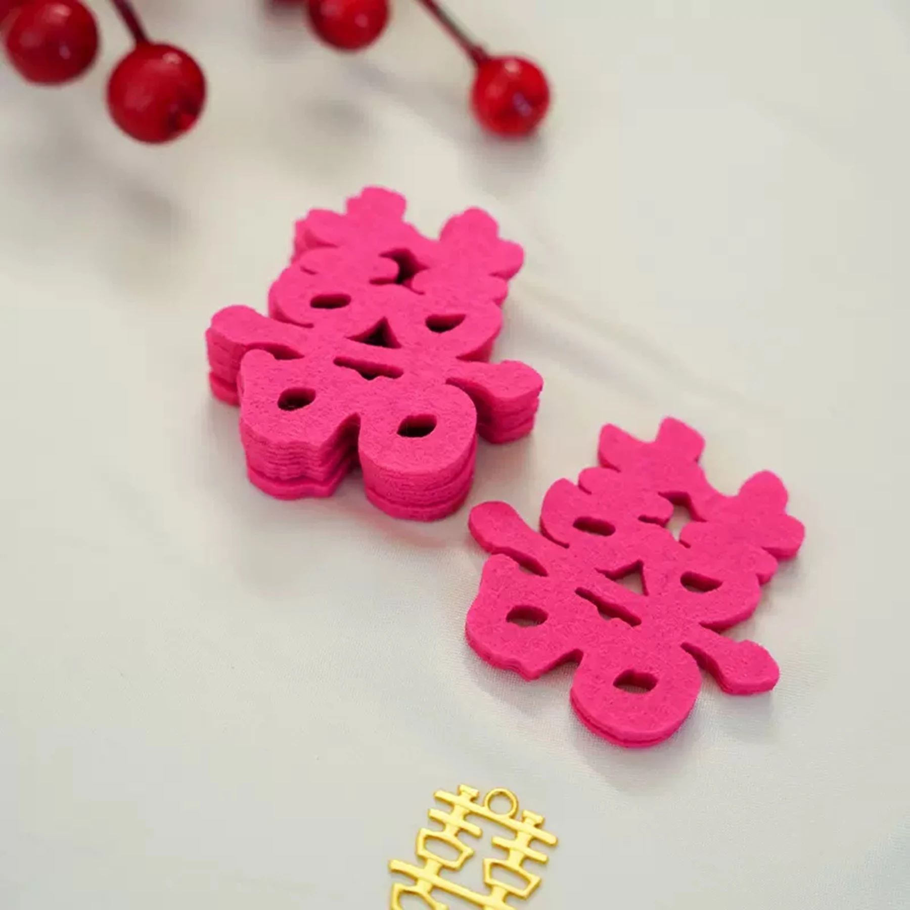 May include: Two pink felt Chinese double happiness symbols, also known as "shuang xi", on a white background. A gold double happiness symbol is in the lower right corner of the image.